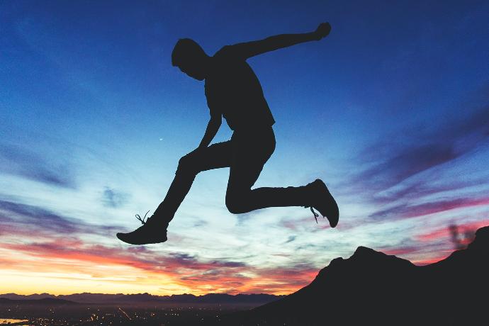 silhouette of man jumping near mountain